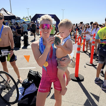 Rebekah Van Natta with her Cal Tri LA medal holding her son William at the finish