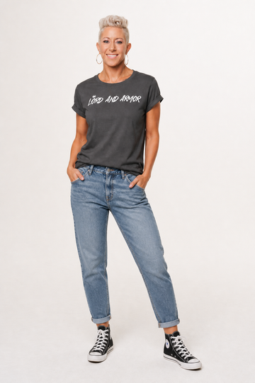 Person wearing a dark gray t-shirt with text and light blue jeans on a white background